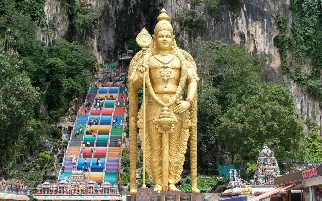 Majestic golden Lord Murugan statue stands before vibrant Batu Caves entrance in Selangor, Malaysia