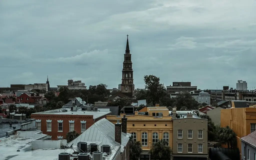 A picturesque view of Charleston, SC, featuring a historic church tower amidst vibrant buildings