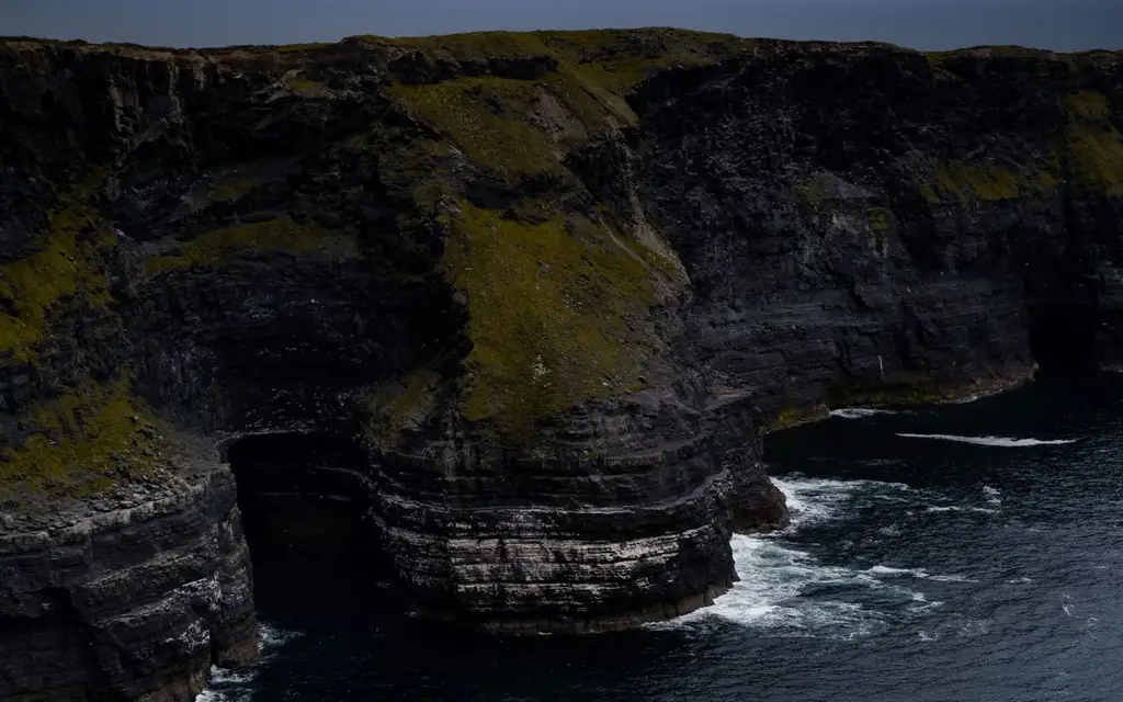 Stunning view of rugged cliffs with ocean waves crashing below on a gloomy day