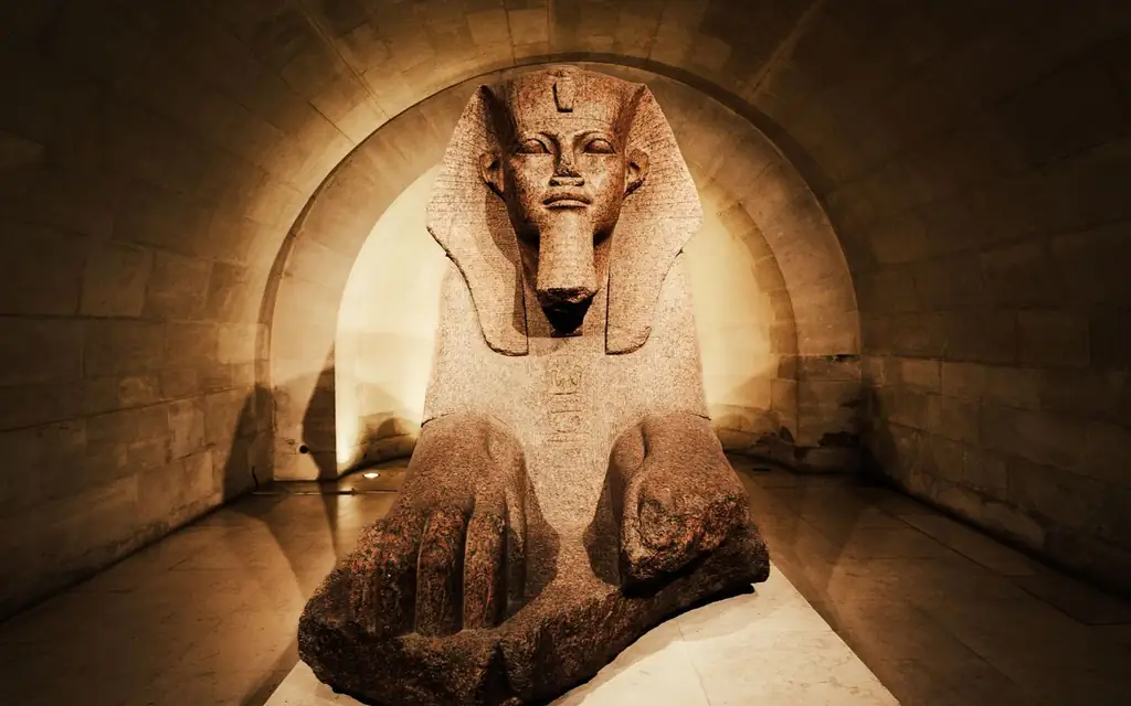 A captivating ancient Egyptian sphinx statue displayed inside a dimly lit museum corridor