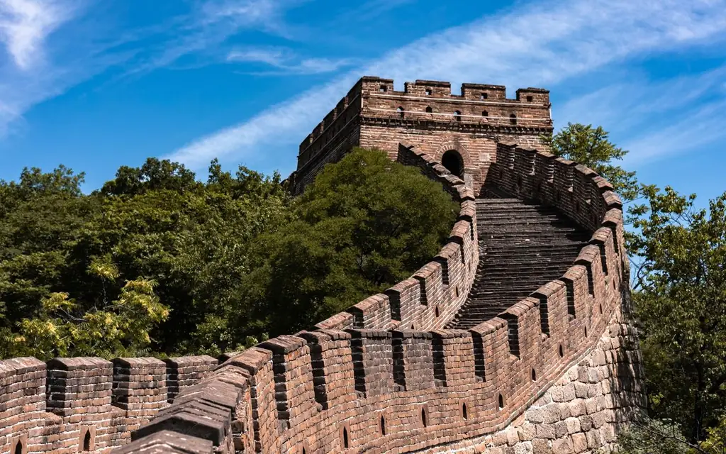 The Great Wall of China surrounded by lush greenery under a clear blue sky