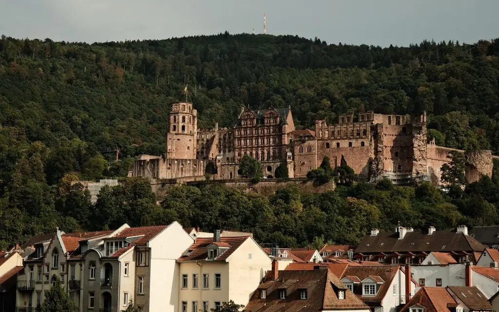 View of Heidelberg Castle overlooking traditional German rooftops against lush greenery