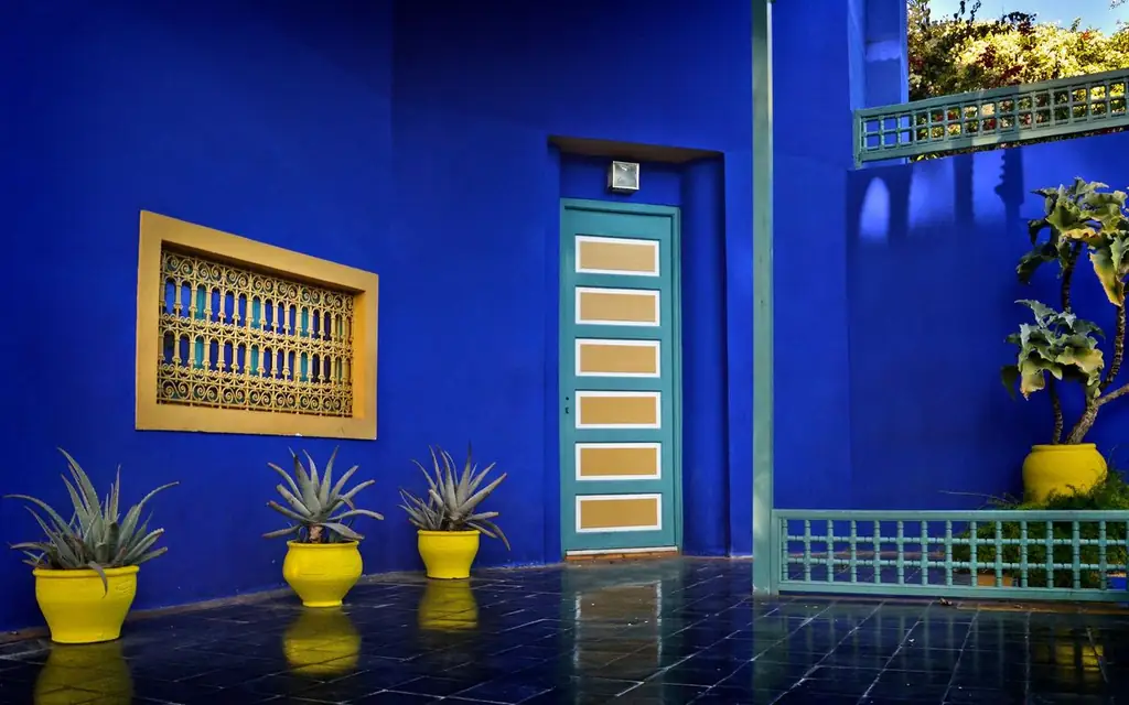 Colorful Moroccan courtyard with blue walls and yellow planters in Marrakech