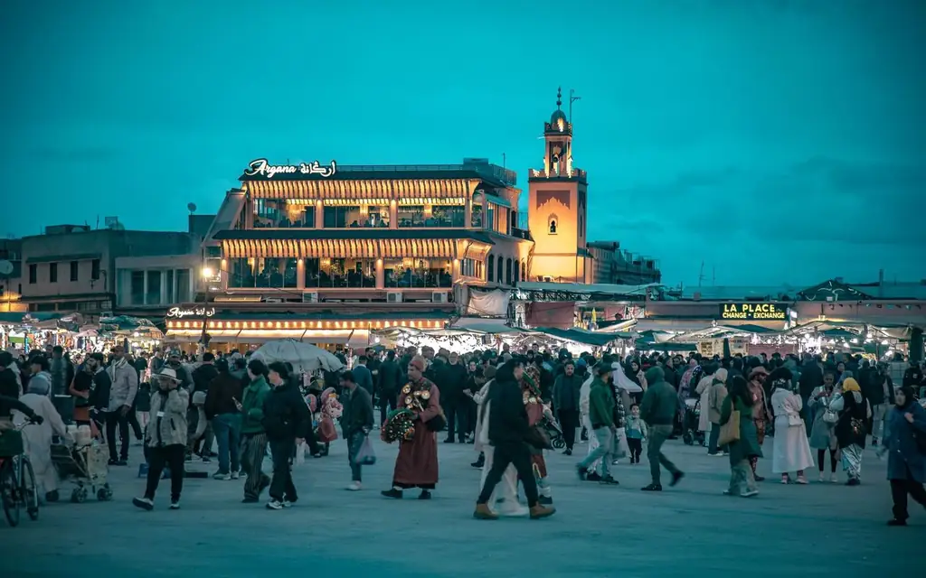 Crowd gathered at iconic Jemaa el-Fnaa square in Marrakesh during dusk, vibrant and lively atmosphere