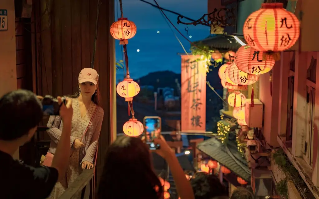 Couple enjoying the illuminated streets of Jiufen at dusk, surrounded by traditional lanterns