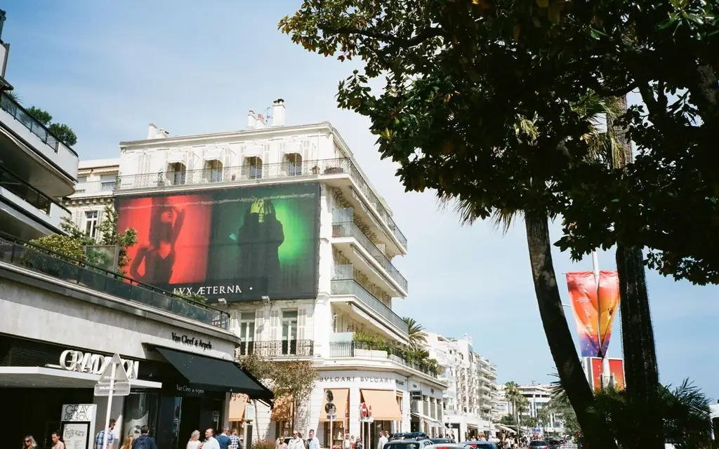 Daytime view of a bustling city street lined with luxury stores and vibrant billboards