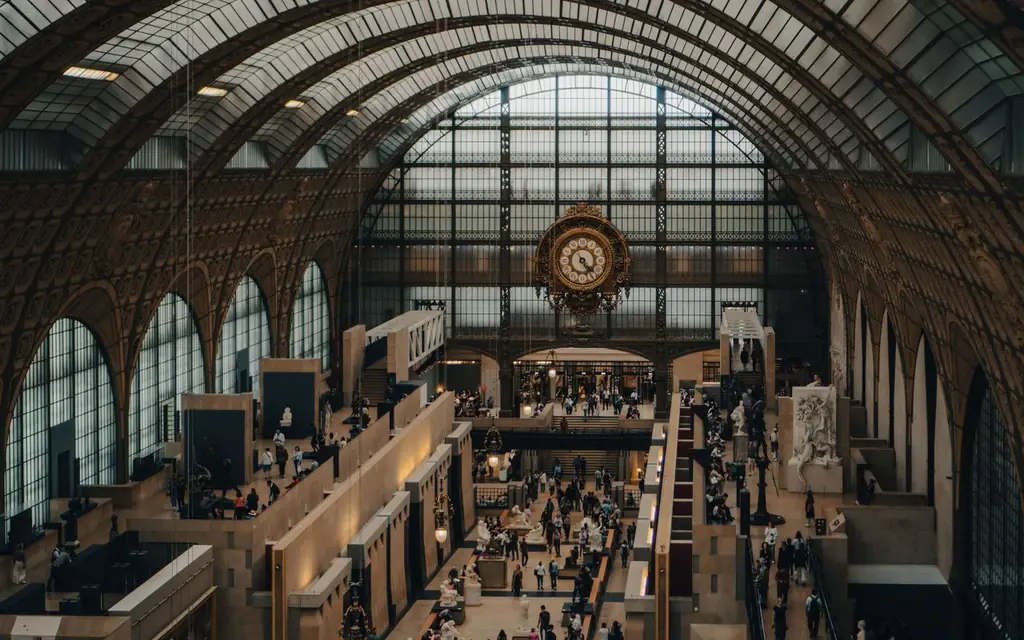 A bustling gallery inside Musée d'Orsay featuring a historic clock and crowds of visitors