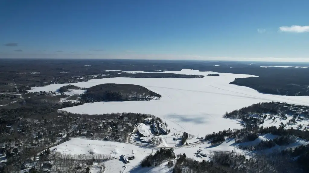 A stunning aerial view of a frozen landscape in Huntsville, Ontario, featuring snow-covered forests and icy lakes