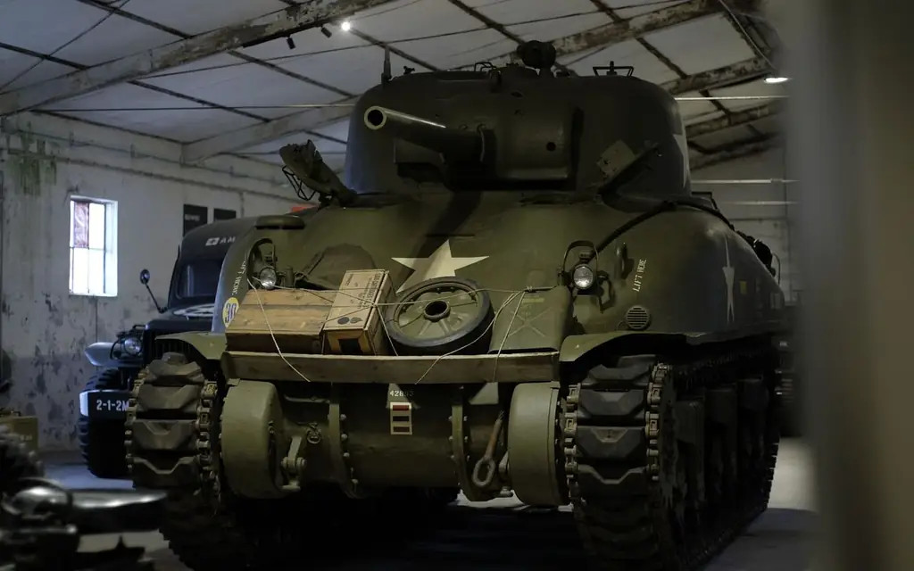 Close-up of an iconic WWII Sherman tank exhibited indoors in a historic museum setting
