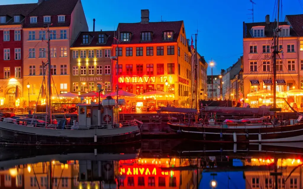 Nyhavn's vibrant waterfront and boats reflected at dusk in Copenhagen, Denmark