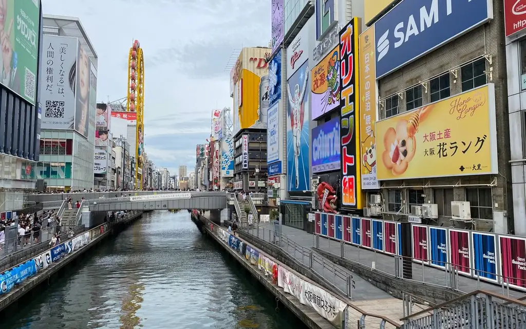 Vibrant street scene of Dotonbori Canal with colorful signs and busy pedestrians in Osaka, Japan