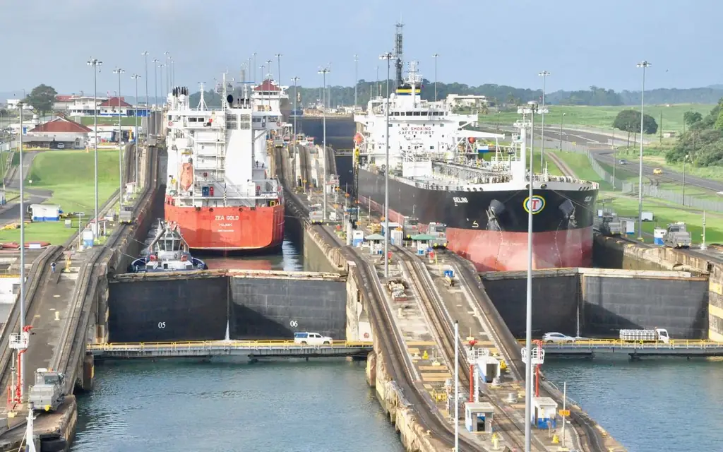 Cargo ships navigating the Panama Canal locks on a clear day, showcasing a bustling transportation hub