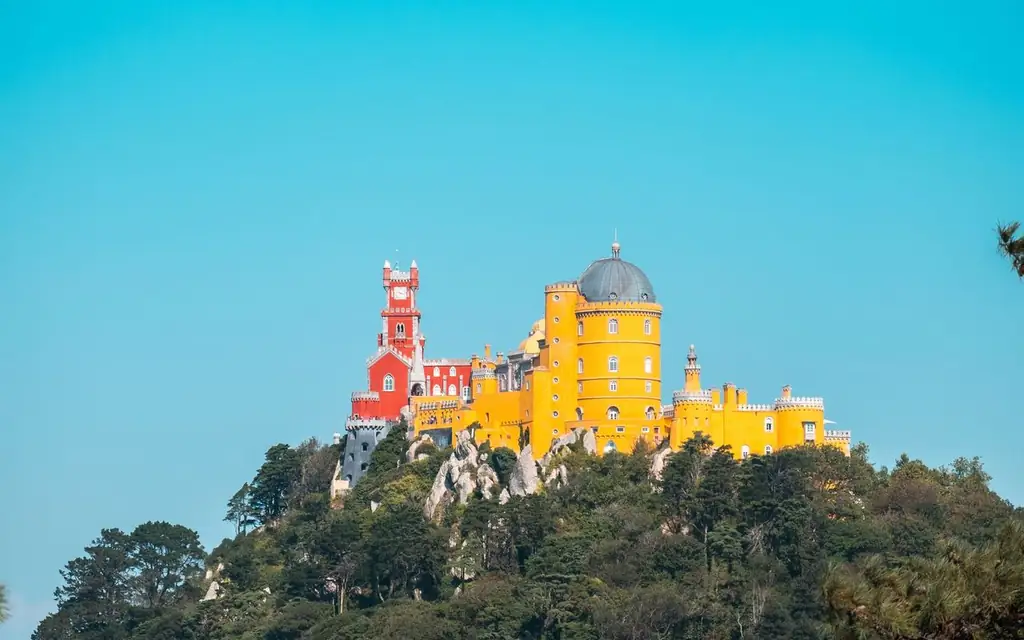 Vibrant Pena Palace on a hilltop in Sintra, Portugal contrasting with a clear blue sky