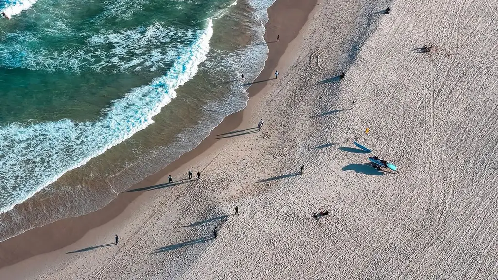 A scenic aerial view of Bondi Beach with scattered people and surf, showcasing the vibrant coastal vibe