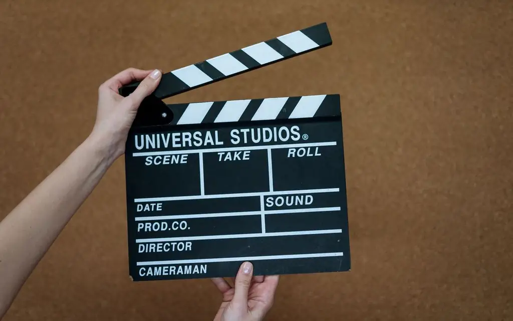 Close-up of hands holding a Universal Studios clapboard on a cork backdrop, ready for filming