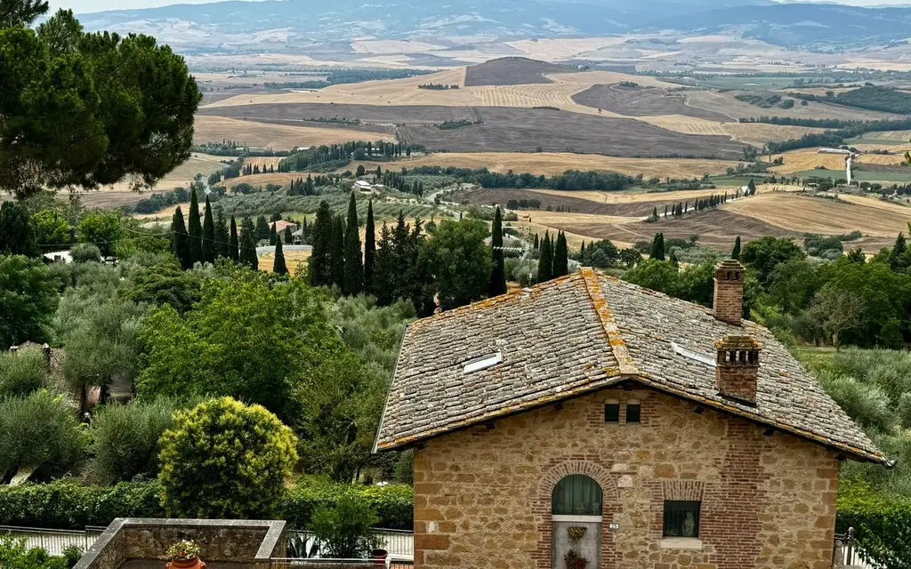 Scenic view of a rustic house in Val d'Orcia, Tuscany, Italy with rolling hills and lush greenery