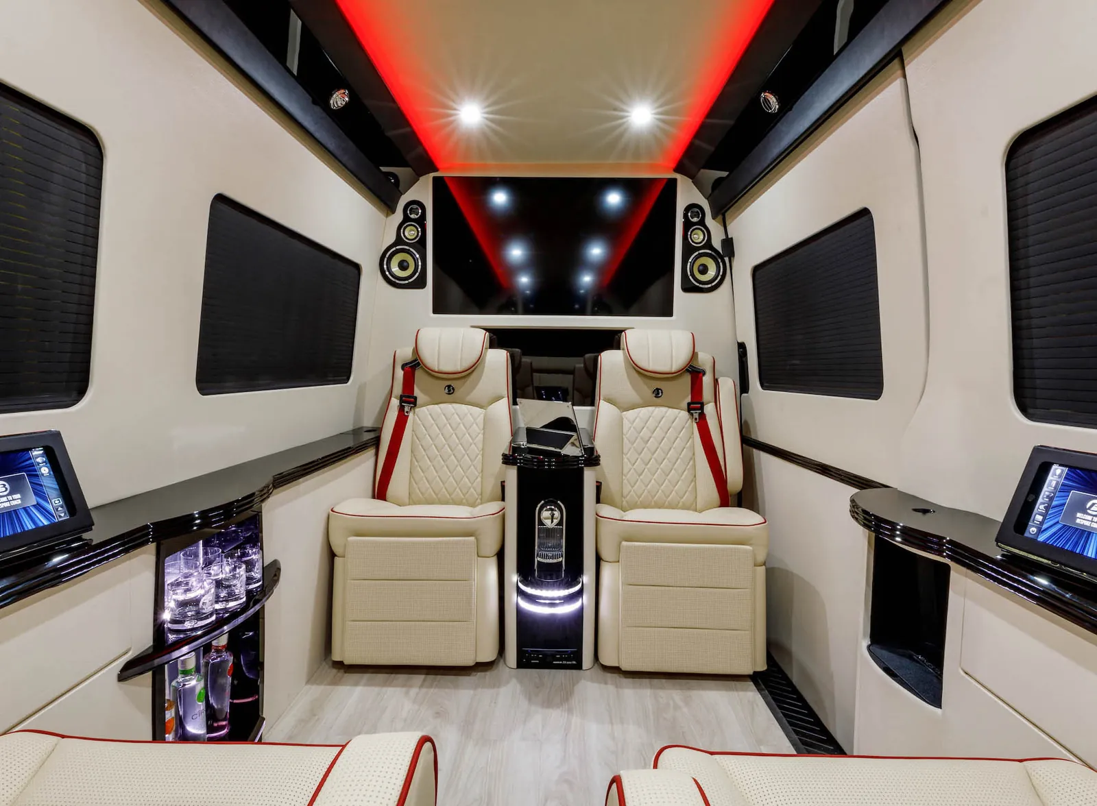 Executive Sprinter cabin in cream leather with two reclining captain's chairs, a centre console, tablets, a bar cabinet and a large screen