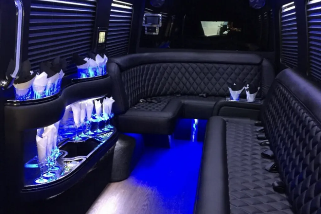 Jet Sprinter lounge interior with quilted leather wraparound seating, a lit bar console and blue floor lighting