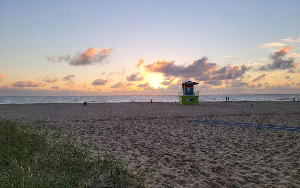 A tranquil sunrise over Fort Lauderdale Beach with a vibrant lifeguard tower and golden sands