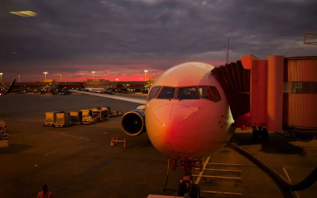 Plane boarding at sunset with vibrant sky colors and airport lights