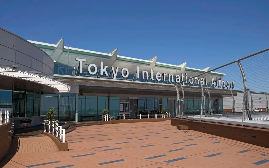 A sunny day view of Tokyo International Airport's entrance with clear blue skies