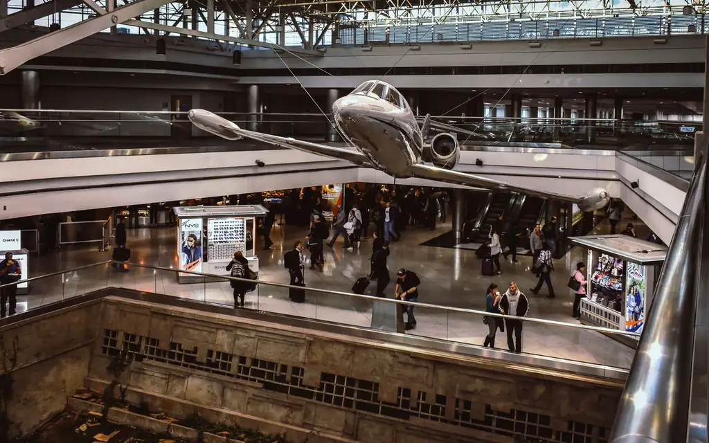 Inside a bustling airport with a hanging airplane and busy travelers