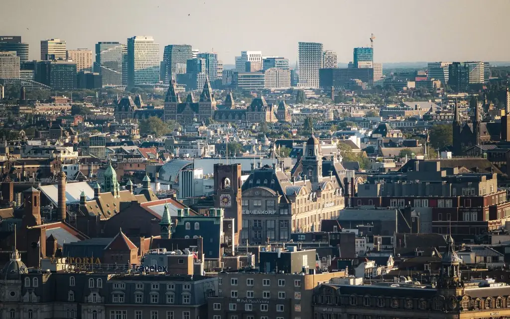 Expansive aerial view of Amsterdam cityscape featuring historic and modern architecture under clear skies