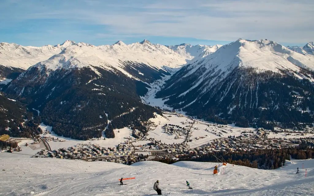 A stunning view of Davos ski slopes with skiers and snow-covered Alps in winter