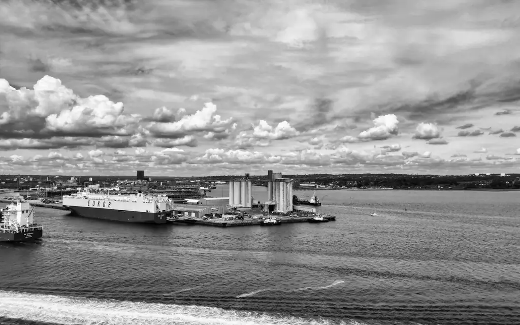 Monochrome aerial view of a port with dramatic sky and sea waves