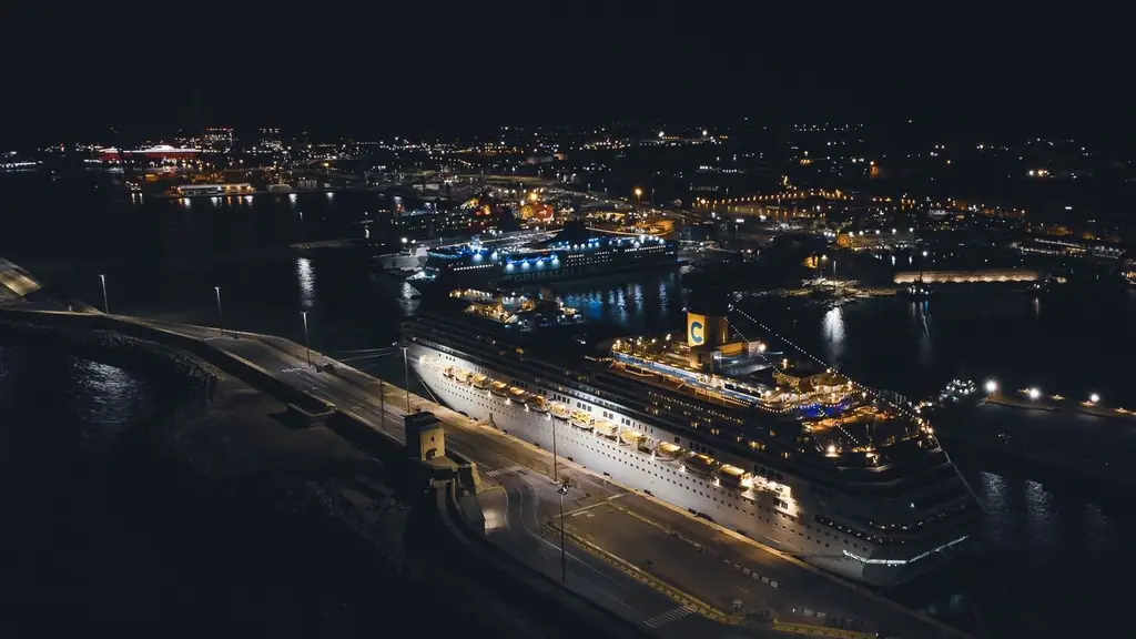 Stunning aerial view of a brightly illuminated cruise ship docked in a bustling harbor at night