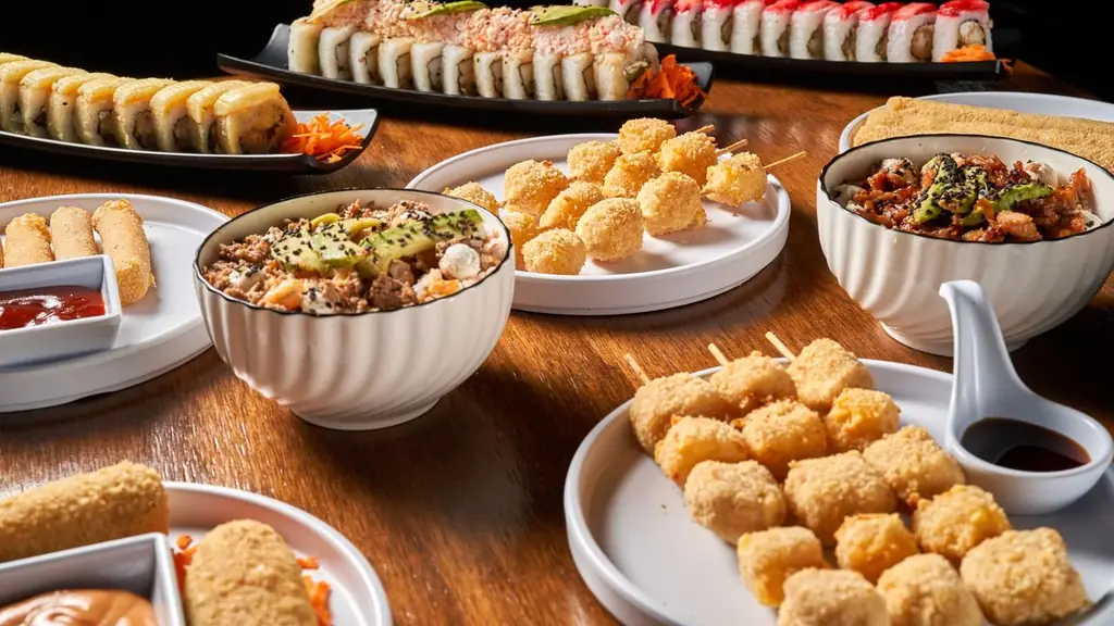 A variety of Asian dishes including sushi, skewers, and rice bowls on a wooden table