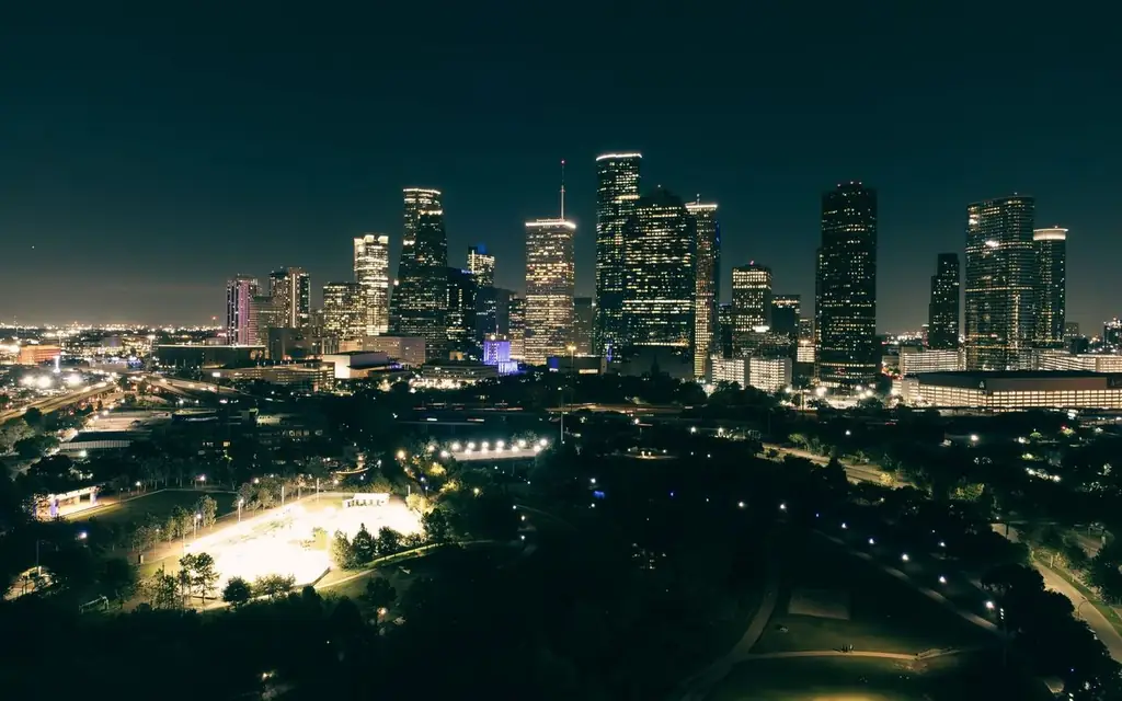 A stunning aerial view of Houston's illuminated skyline at night, showcasing skyscrapers and urban parks