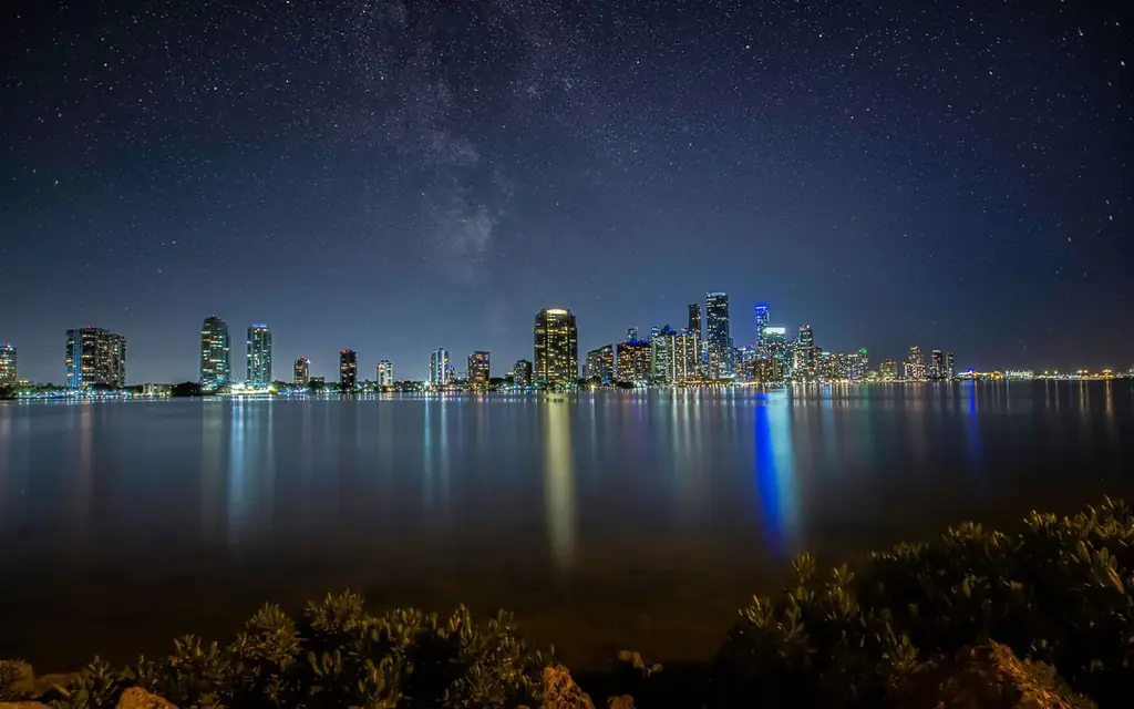 Breathtaking view of Miami's skyline at night with a star-filled sky reflecting over the water