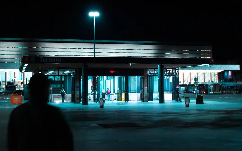 Illuminated entrance of Rome Termini Station at night with people in view