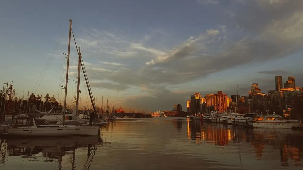 A stunning view of boats docked at a marina during golden hour, with the Vancouver skyline bathed in warm sunset light