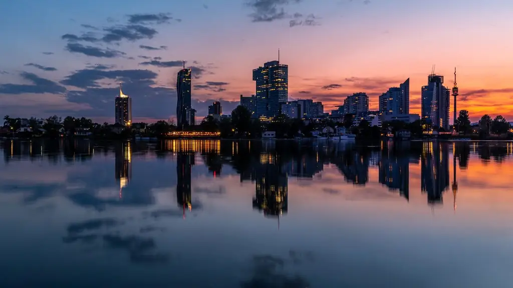 Tranquil reflection of Vienna's cityscape at sunset, showcasing serene waters and vibrant skies