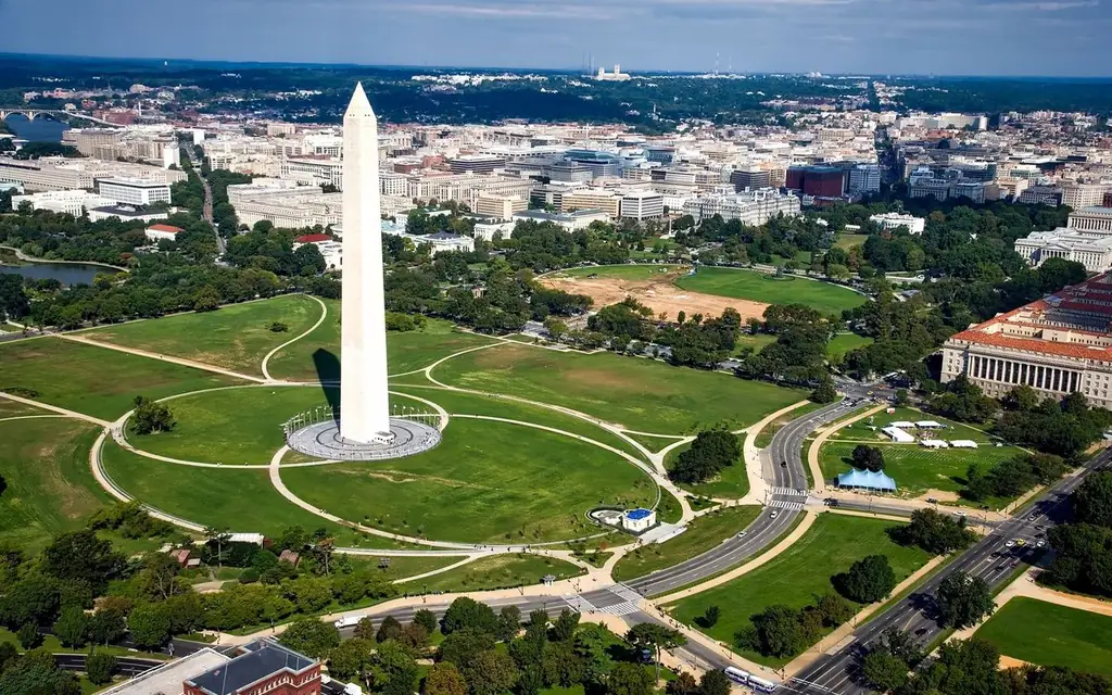 A breathtaking aerial view of the Washington Monument surrounded by cityscape and green landscapes